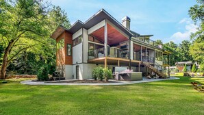 Ein modernes, zweistöckiges Haus mit überdachter Terrasse, einer Treppe und einem gepflegten Rasen.