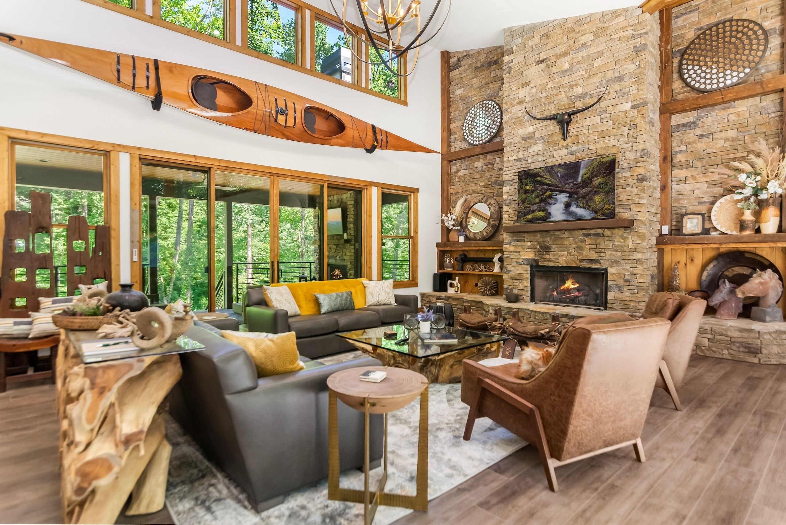 A spacious living room with a large sofa, a fireplace, and a high ceiling with wooden beams.
