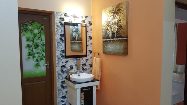 Un baño con un lavamanos blanco, un espejo y dos cuadros colgados en la pared.