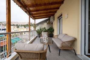 A balcony with wicker furniture, potted plants, and a view of the cityscape.