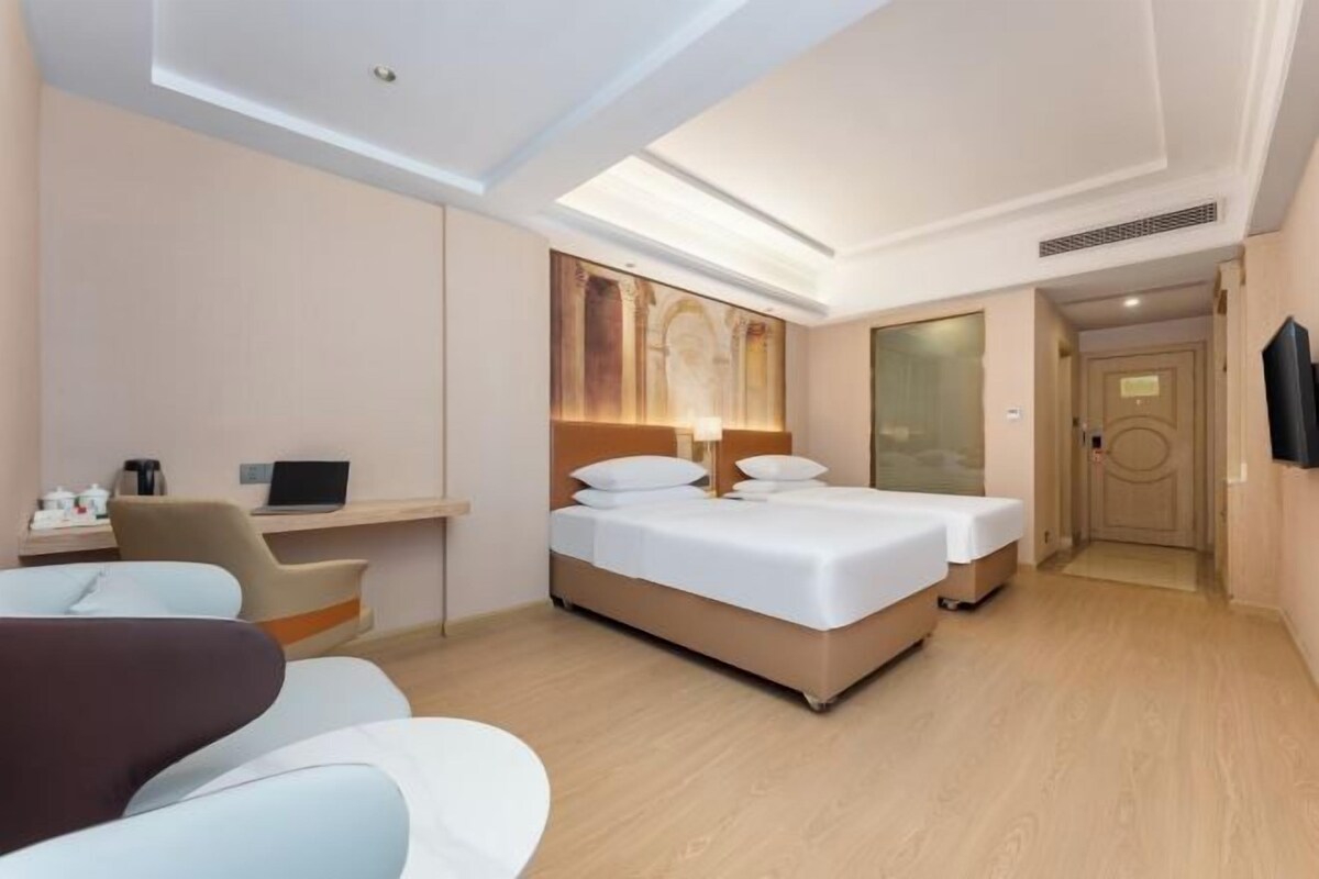 A hotel room with a bed, desk, chair, and a television.