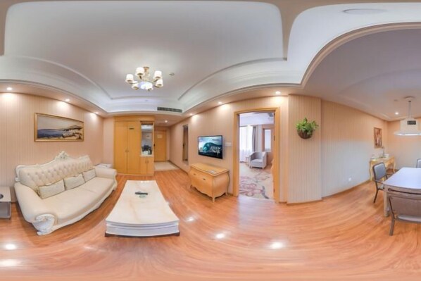 A spacious living room with a large sofa, a coffee table, and a television. The room has wooden flooring and a high ceiling with decorative molding. - Vienna Hotel (Pingxiang Runda international Pedestrian Street) (Pingxiang)