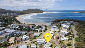 Vista aérea de una zona residencial costera con casas, una playa y una vista despejada del océano.