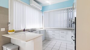 Una cocina moderna con armarios blancos, encimera blanca y lavavajillas integrado.