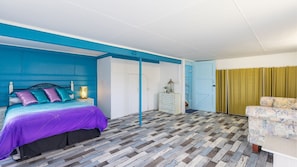 Ein Schlafzimmer mit Bett, Kommode, Stuhl und Tür.