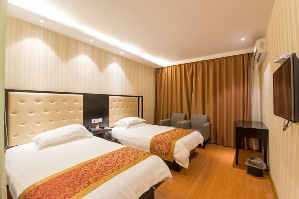 A hotel room with two beds, a TV, a desk, and a chair.