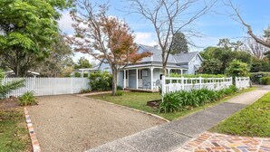 A residential property with a covered porch, a fenced yard, and a gravel driveway.