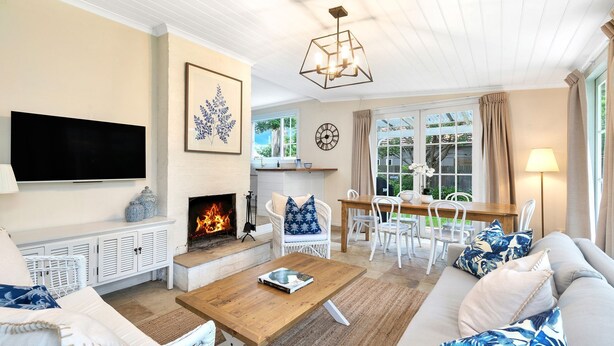 A living room with a fireplace, a TV, and a dining area with white furniture.