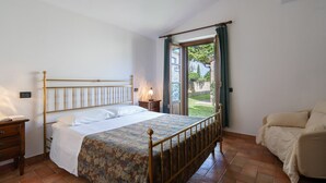 A bedroom with a bed, bedside tables, a chair, and a window with curtains. - Rocche di Valiano, Gelsomino in Siena, pool use, AC (Castelnuovo Berardenga)