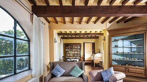 Un salon chaleureux avec une grande fenêtre, une cheminée, une bibliothèque et une vitrine.
