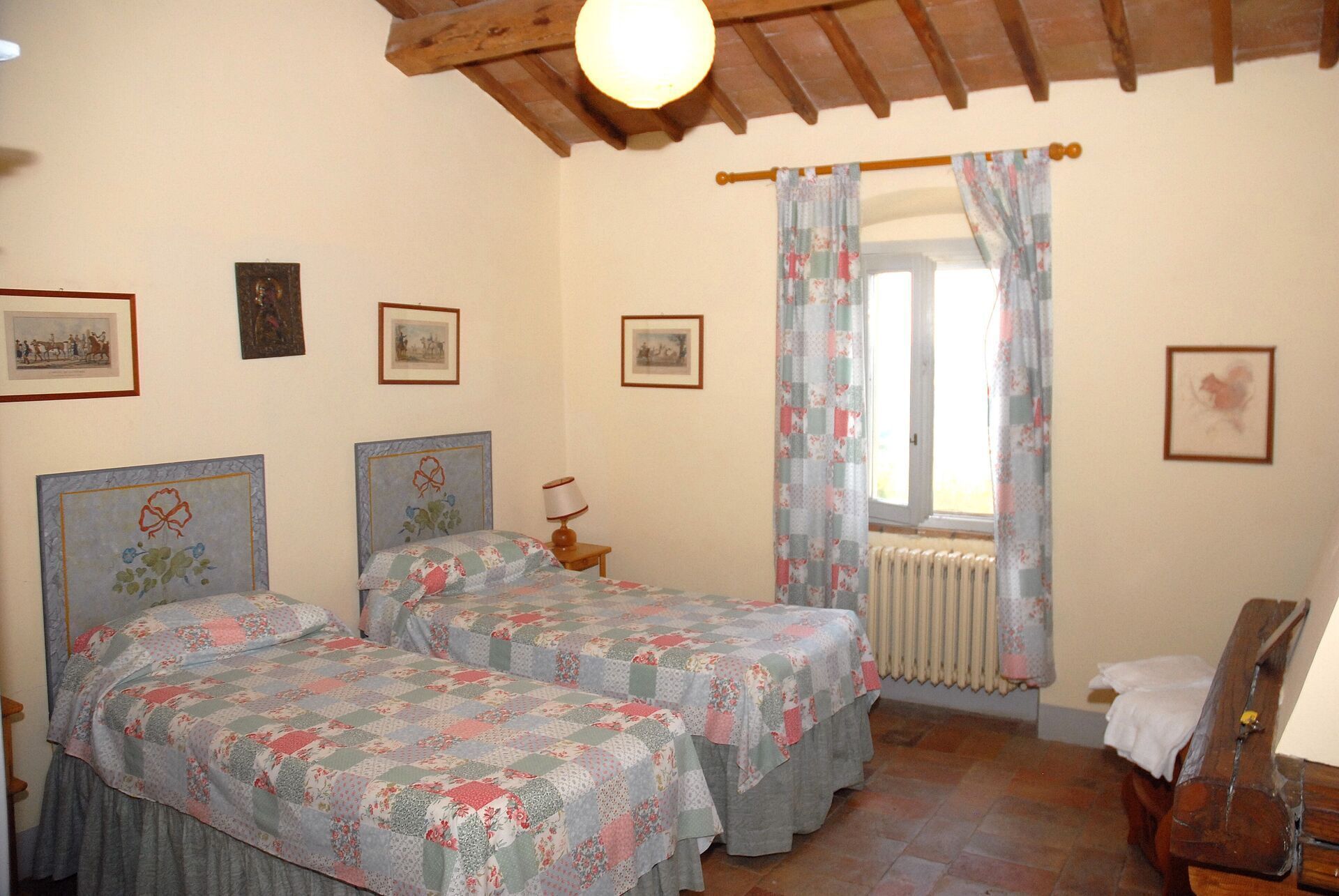 Una camera da letto con due letti, un soffitto in legno, un termosifone e diverse foto appese alle pareti.