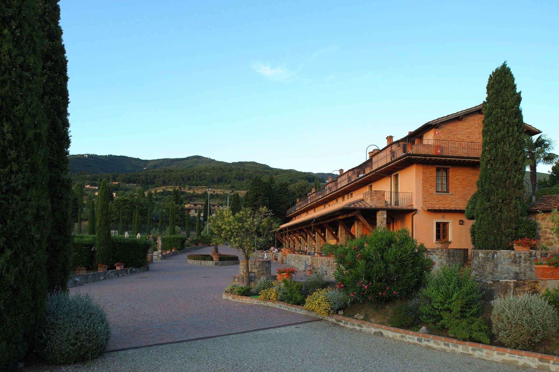 A traditional building with a stone facade, a balcony, and a garden with various plants and flowers.