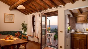 A cozy dining area with a table set for two, a wooden bench, and a view of the outdoors through an open door. - Residence in San Donato Fronzano with 2 bedrooms sleeps 4 (San Donato Fronzano)