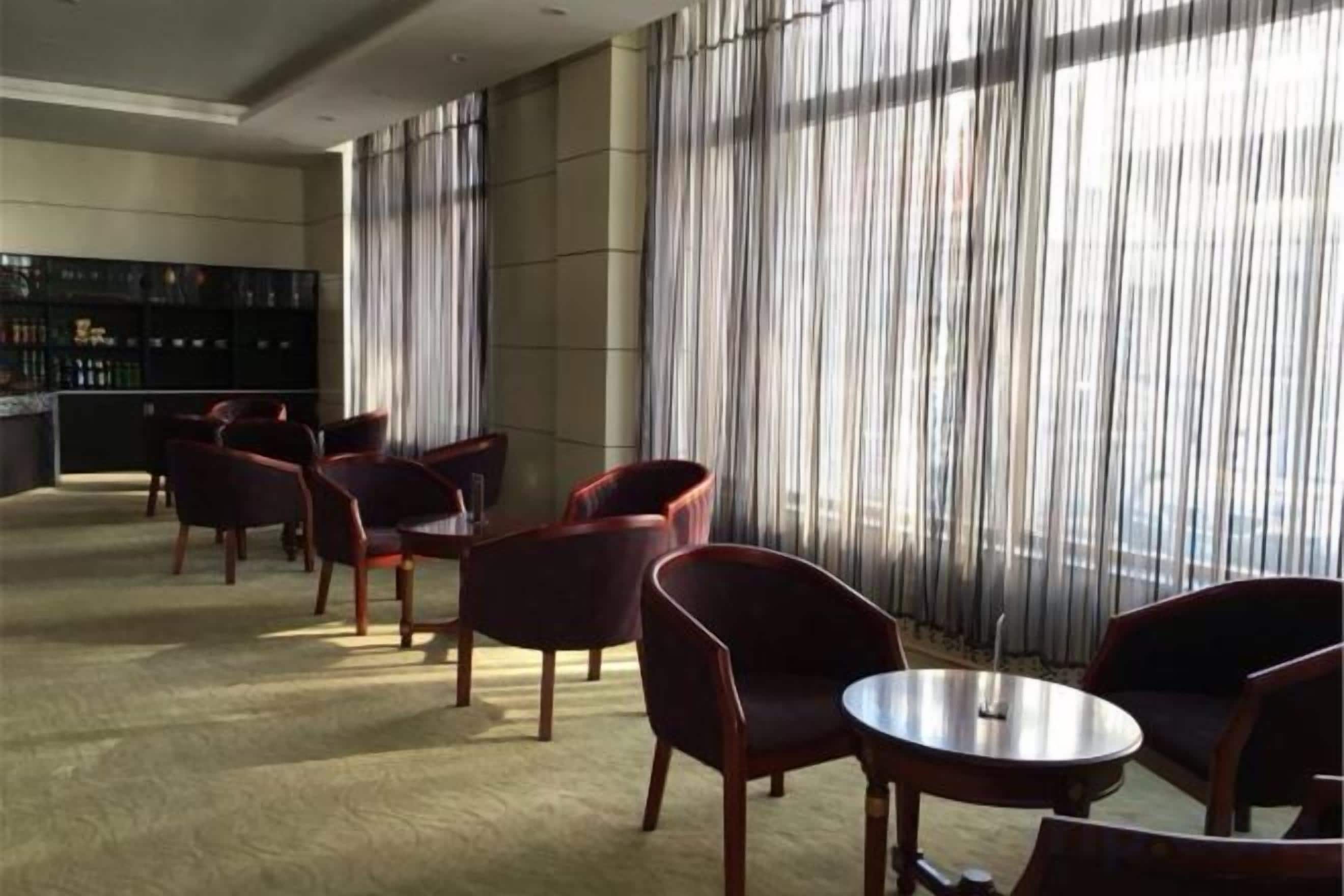 A hotel lobby with a bar area, seating arrangements, and large windows.