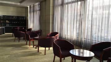 A hotel lobby with a bar area, seating arrangements, and large windows.