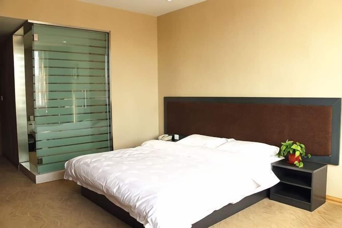 Une chambre à coucher avec un lit, une table de chevet, une porte coulissante verte et une plante en pot.