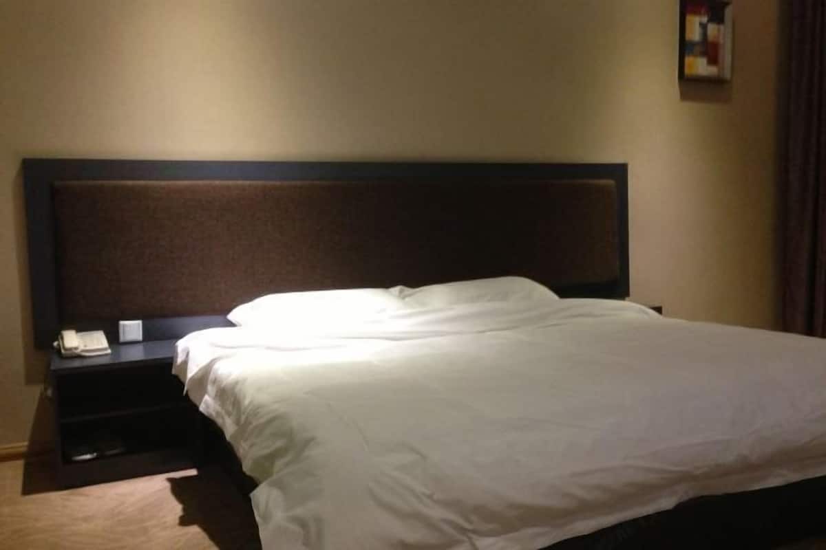 Un lit bien fait, avec du linge de lit blanc, dans une chambre d’hôtel.