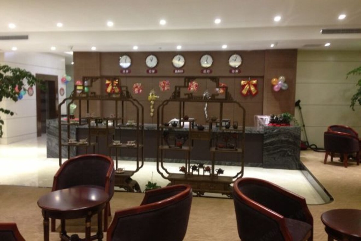 A lobby with a reception desk, chairs, and a decorative wall with clocks and flowers.