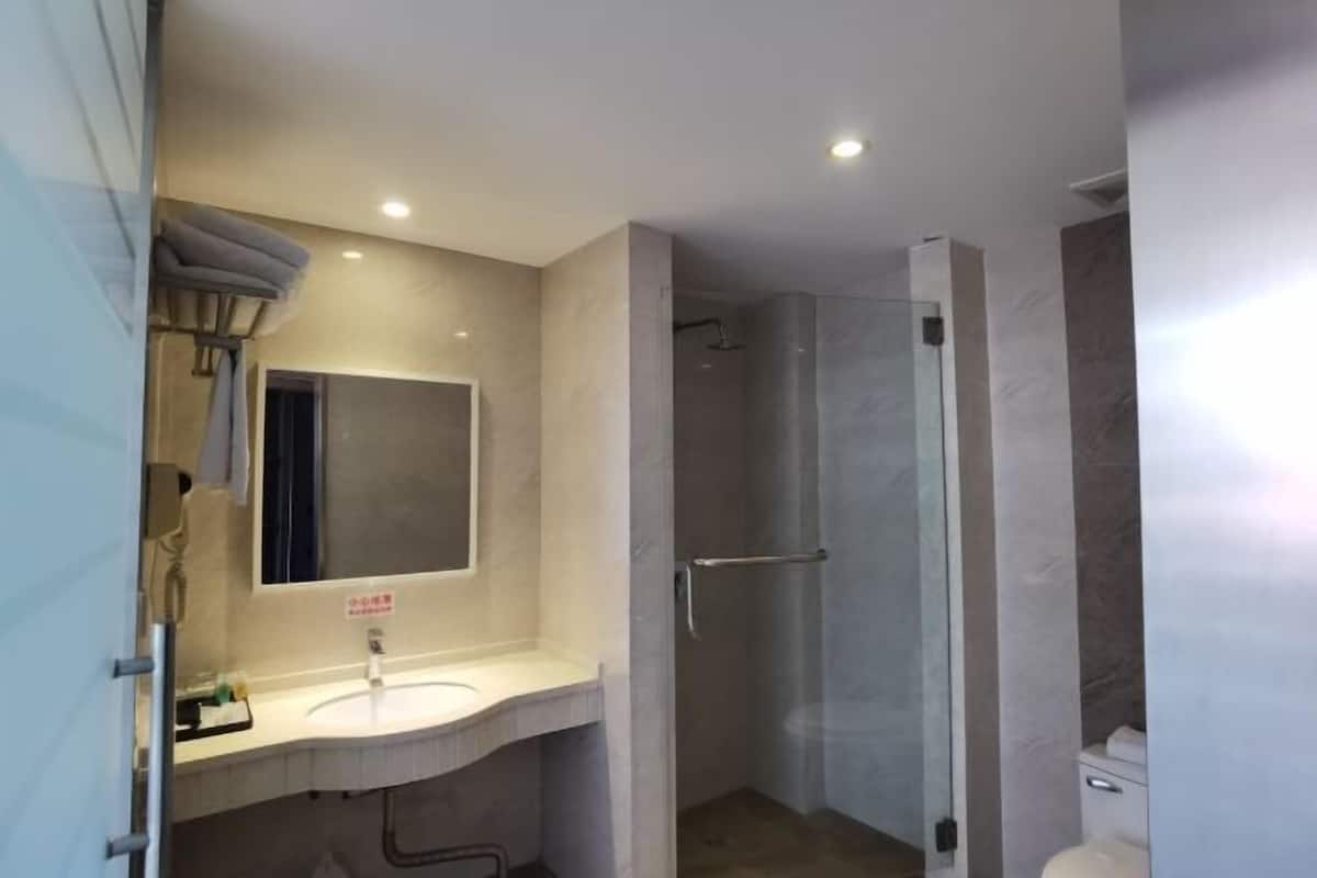 Une salle de bain moderne équipée d’une douche, d’un lavabo avec un miroir et de toilettes.