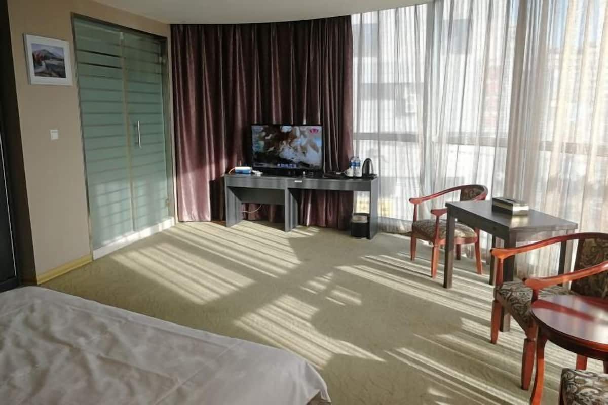 Une chambre d’hôtel comprenant un lit, un bureau avec une télévision et un coin repas avec des chaises.