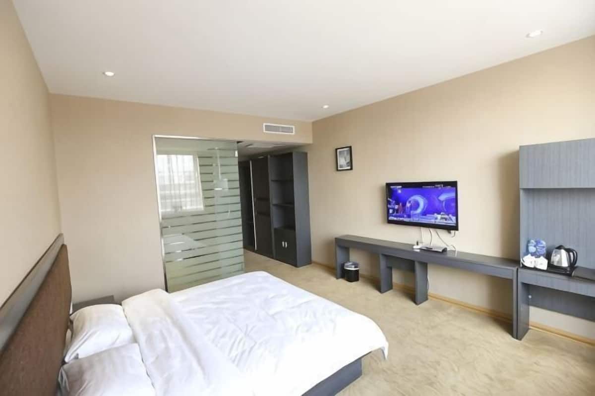 Une chambre d’hôtel comprenant un lit, une télévision, un banc et une armoire.