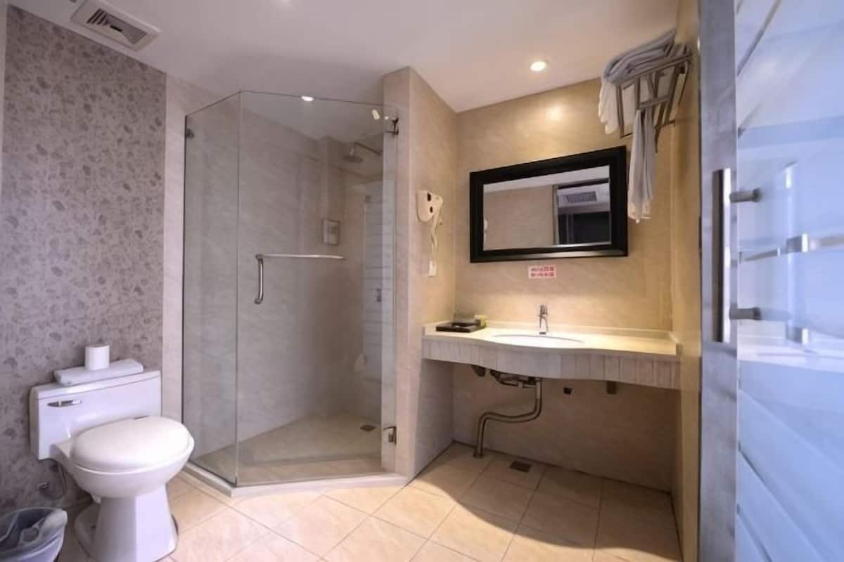 Une salle de bain avec une douche à parois de verre, des toilettes, un lavabo et un miroir.
