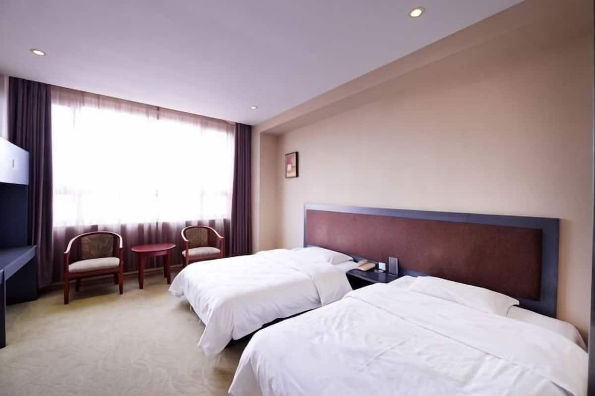 Une chambre d’hôtel avec deux lits, un bureau, une chaise et une petite table.
