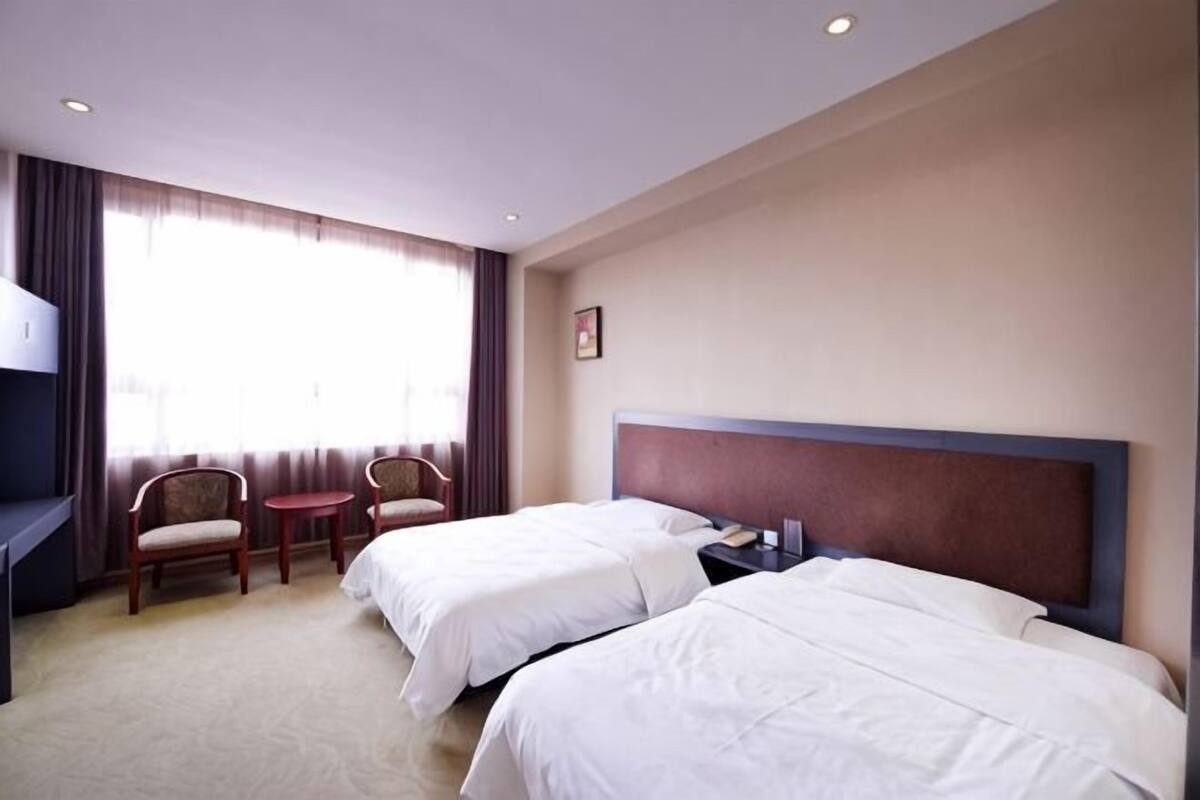 Una habitación de hotel con dos camas, un escritorio, una silla y una mesita.