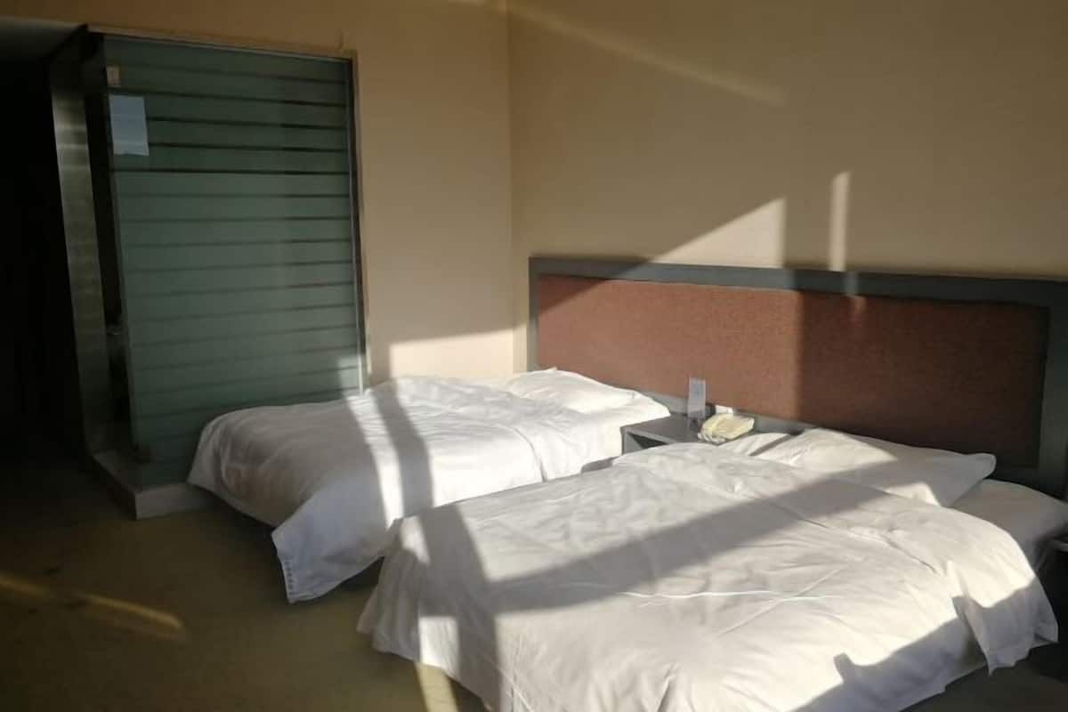 Une chambre d’hôtel avec deux lits, une table de chevet et une porte fermée.