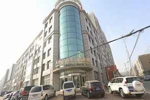 Un hôtel à plusieurs étages, doté d’une façade incurvée, d’une entrée imposante et de plusieurs voitures garées devant.