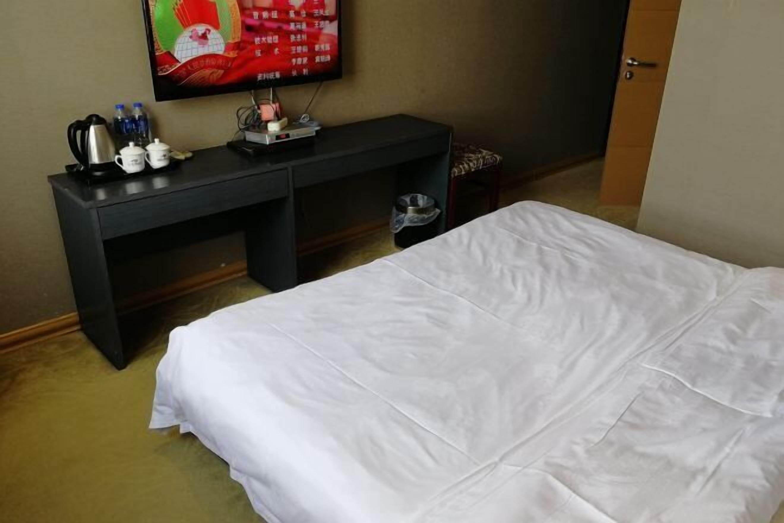A hotel room with a bed, a desk with a television, and a coffee maker.