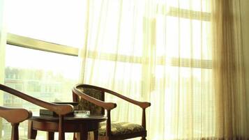 A room with a large window, a round table, and two wooden chairs.