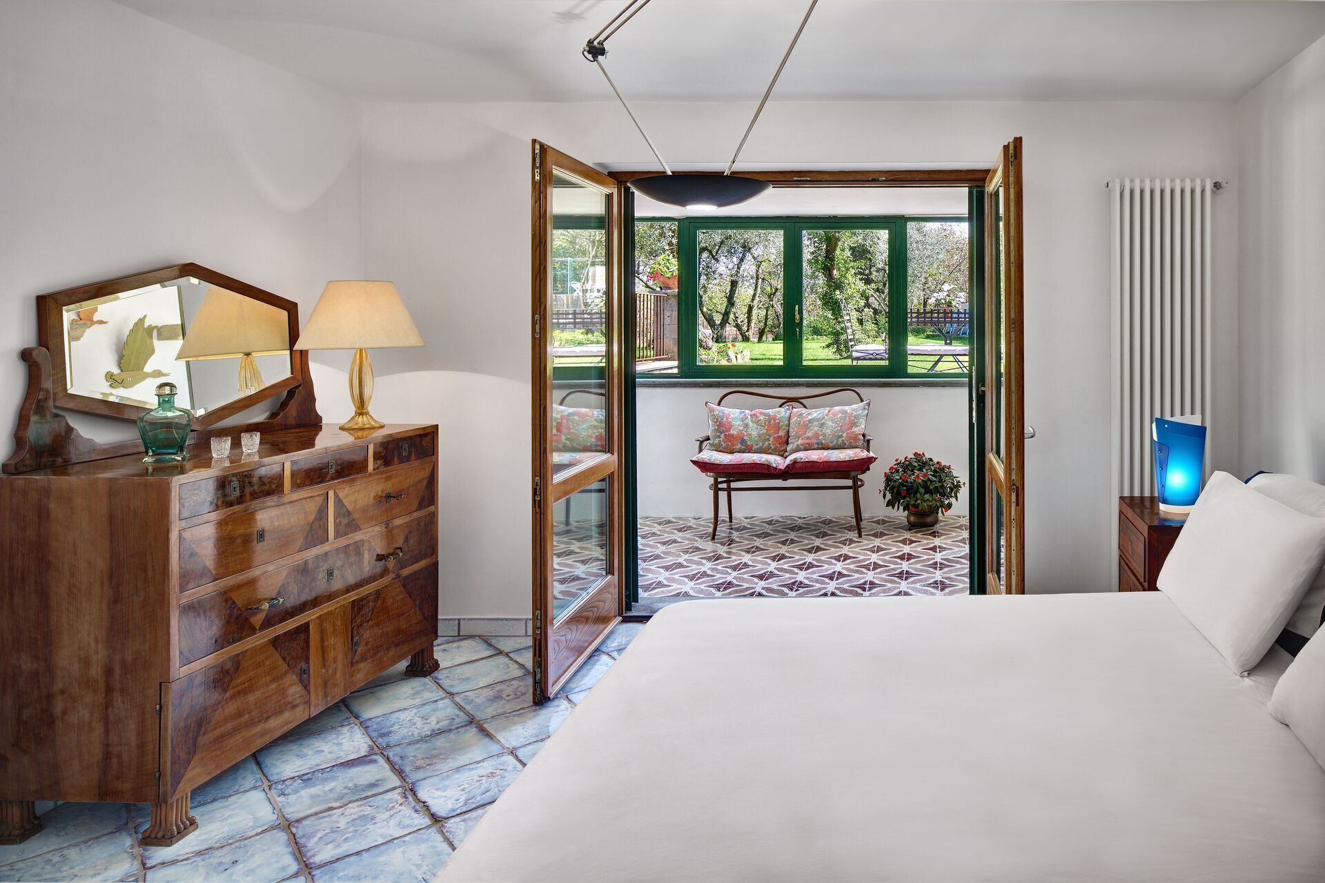 Une chambre avec un grand lit, une commode en bois et une fenêtre donnant sur un paysage verdoyant.