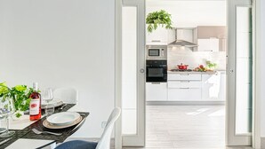 A modern kitchen with built-in appliances, a dining area with a table set for two, and a view into the living space.