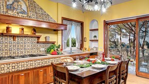A kitchen with a tiled backsplash, wooden cabinets, a dining area with a table set for four, and a view through a glass door.
