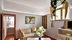 Une pièce comprenant un canapé, une table à manger ornée d’un vase de fleurs, un téléviseur et un escalier menant à une autre pièce.