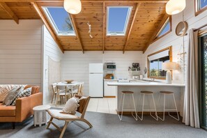 A compact kitchen with a dining area, a bar stool setup, and a cozy seating area with a sofa and chairs. - The Beach Cottage (Separation Creek)