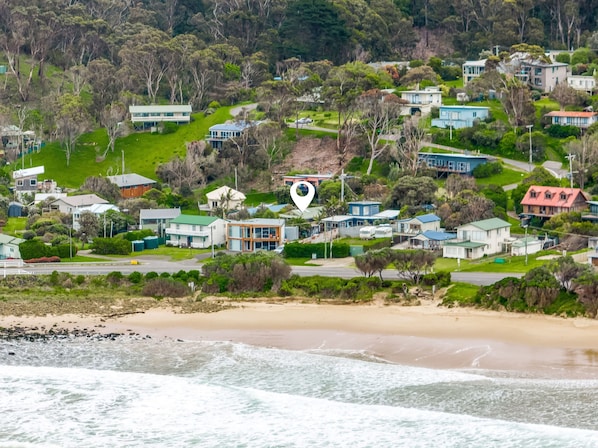 A coastal residential area with houses, a beach, and a road.