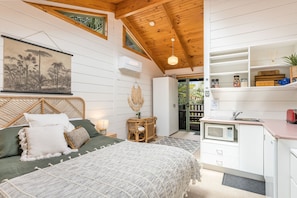 A cozy bedroom with a bed, bedside table, and a view of the outside.