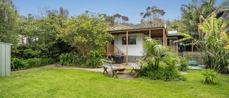 A house with a deck, a barbecue area, and a grassy yard.