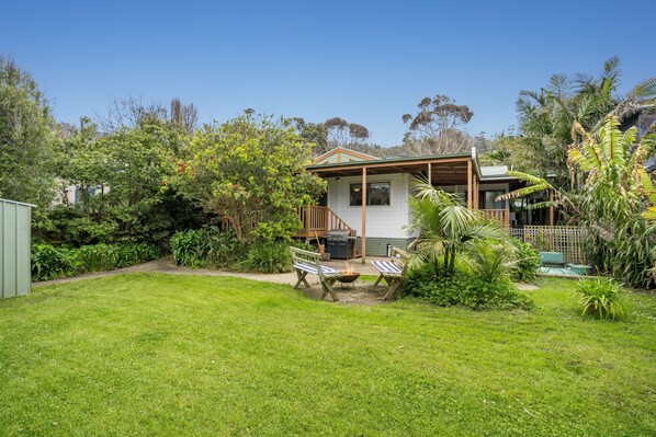 A house with a deck, a barbecue area, and a grassy yard. - The Beach Cottage (Separation Creek)