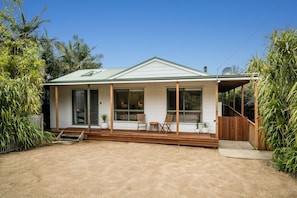 A single-story house with a covered porch, a small deck, and a fenced yard.
