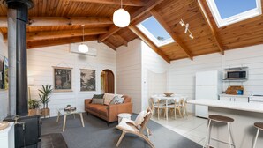 Un loft amplio con techo alto, vigas de madera, chimenea, comedor y cocina.