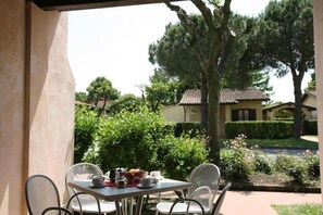 Une terrasse avec une table dressée pour le petit-déjeuner, entourée de verdure et offrant une vue sur les maisons.