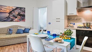 Un apartamento moderno con comedor, kitchenette y sala de estar con sofá y un cuadro grande.
