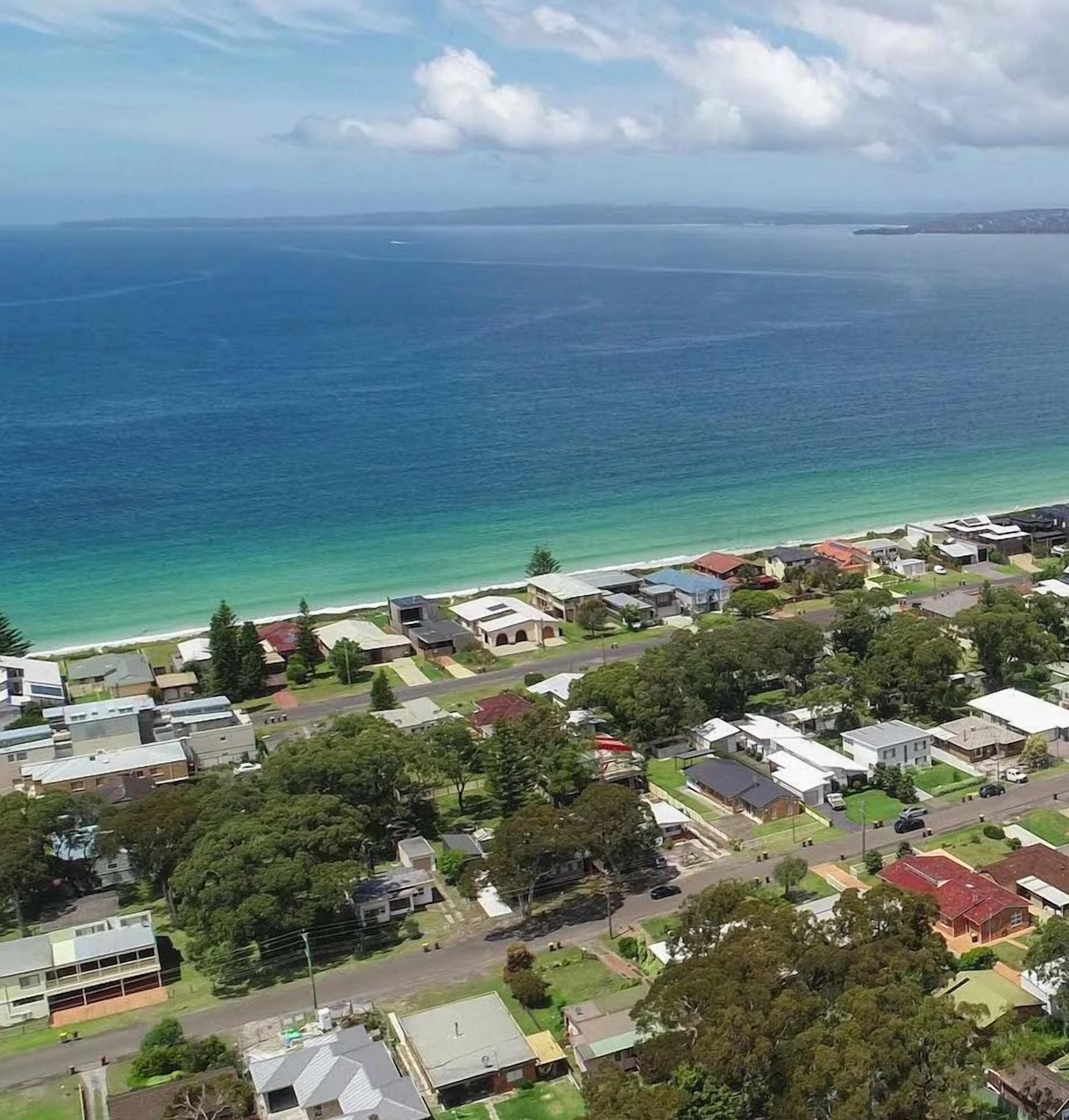 A coastal residential area with houses, roads, and a beach.