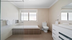 A modern bathroom with a bathtub, toilet, and vanity.