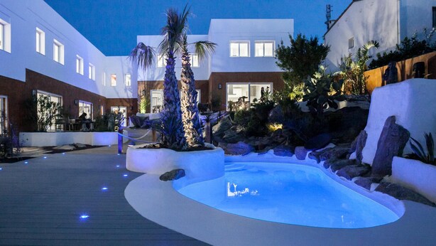 A modern hotel courtyard with a heated swimming pool, palm trees, and a dining area. - 9 Balinese-style Houses with 3 Bedrooms, Communal Pool, and Jacuzzi (Roses)