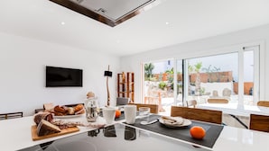 A modern dining area with a large table, chairs, and a view of the outdoors. - 9 Balinese-style Houses with 3 Bedrooms, Communal Pool, and Jacuzzi (Roses)