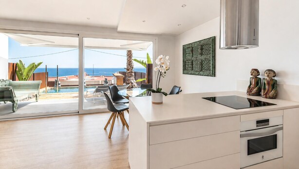 A modern kitchen with a large island, a built-in oven, and a view of the ocean.